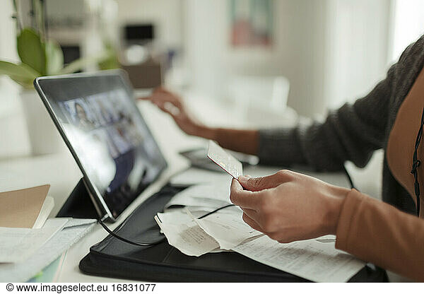 Close up woman with credit card paying bills at digital tablet
