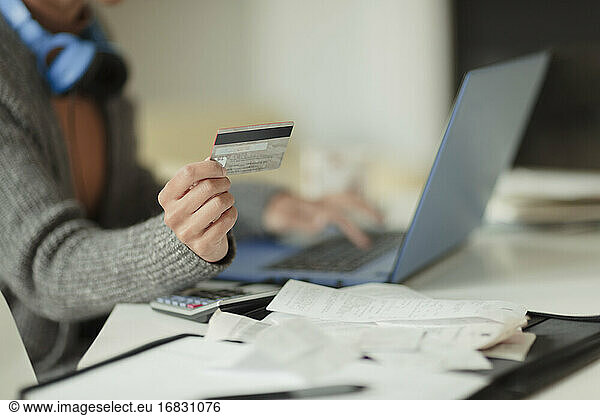 Close up woman with credit card paying bills online at laptop