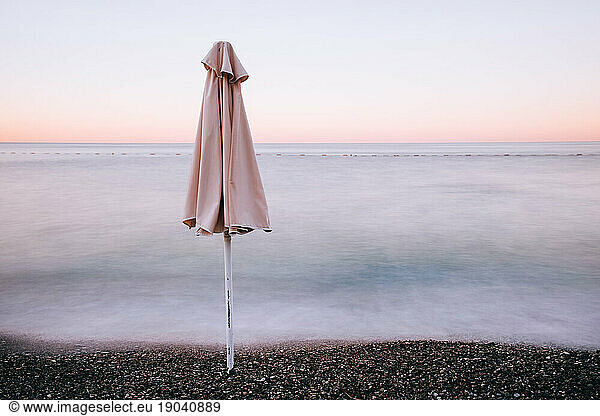 Closed beach umbrella at the sea shore. Long exposure image