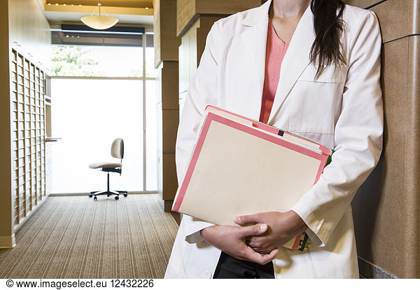 Closeup of a female dentist in her office holding file folders.