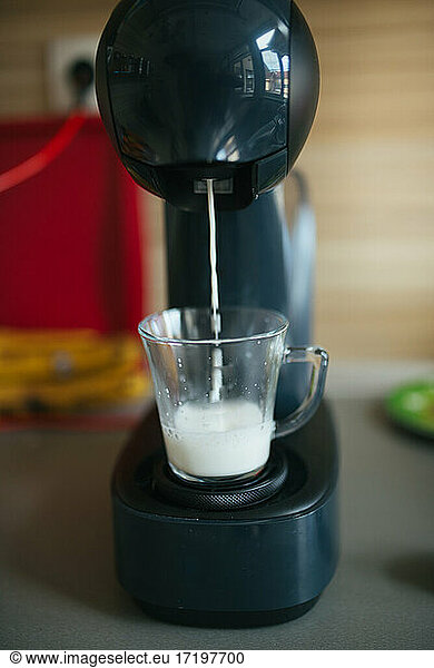 Closeup of milk from espresso machine. Pouring milk into a glass.