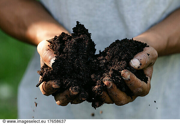 Closeup of two hands holding fresh soil in the sunshine