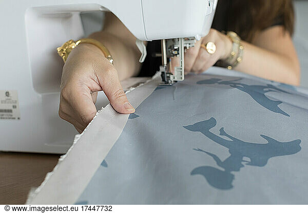 Closeup of woman's hands sewing fabric with electric sewing machine