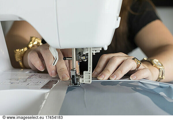 Closeup of woman's hands sewing fabric with electric sewing machine