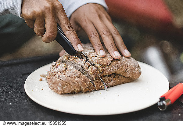 Closeup of women hands cutting bread outdoors