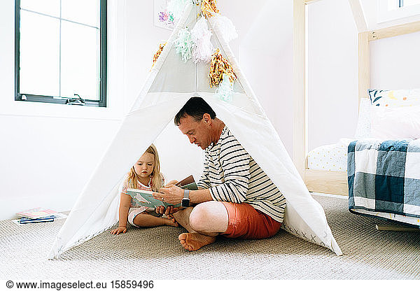 Closeup portrait of a dad and child reading together in a child's room