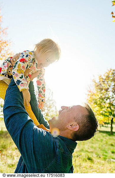Closeup portrait of a father lifting his toddler child into the air