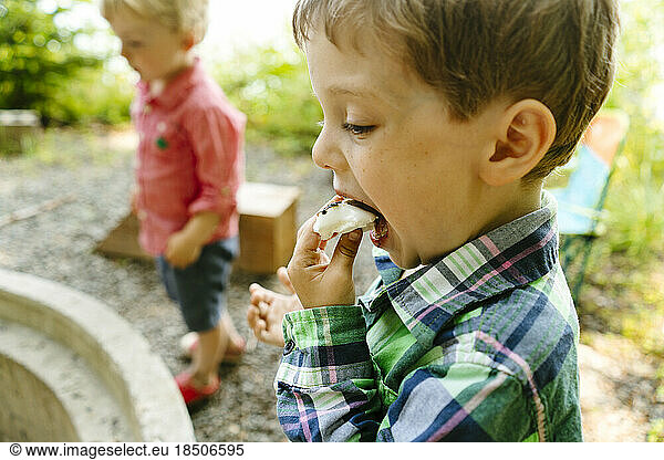 Closeup side view of a young boy eating a marshmallow smore