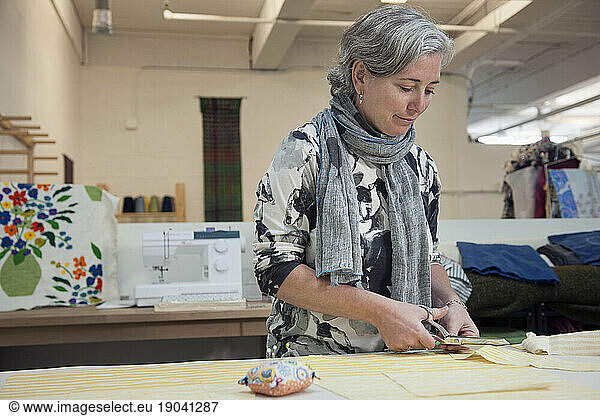 Clothes-maker and fiber artist cuts patterns in studio in Portland  Maine