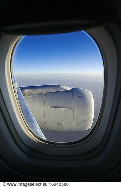 Cloud horizon with engine seen through airplane window.