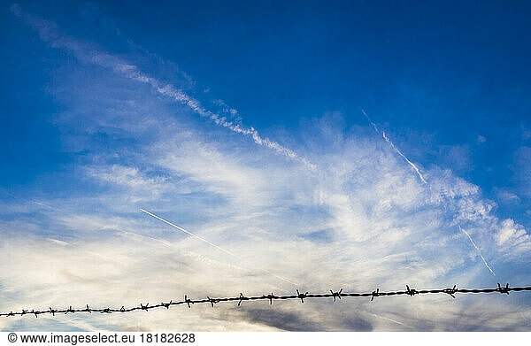 Clouds at dusk with barbed wire in foreground