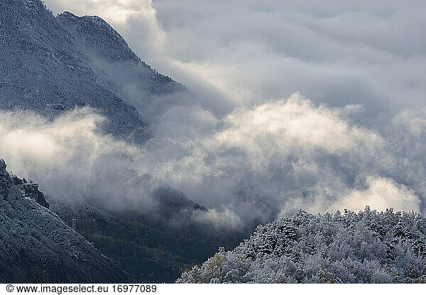 clouds between mountains in a snowy landscape at winter