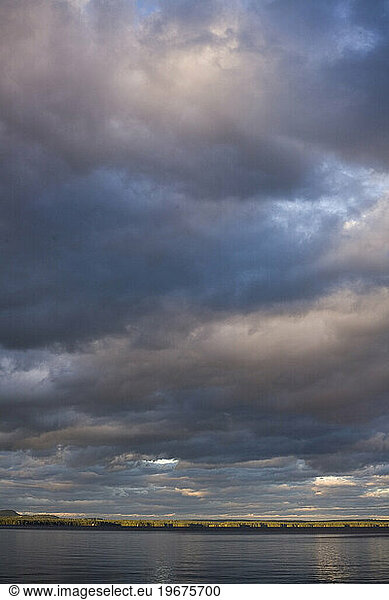 Clouds gather at dusk over the calm waters of Sebago Lake in Maine.