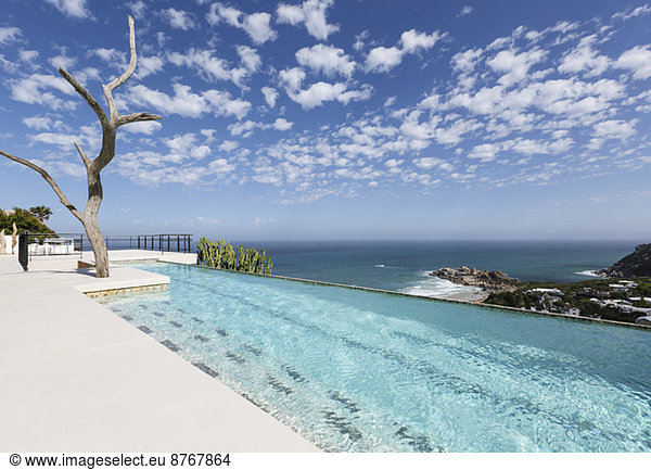 Clouds in blue sky over luxury lap pool overlooking ocean
