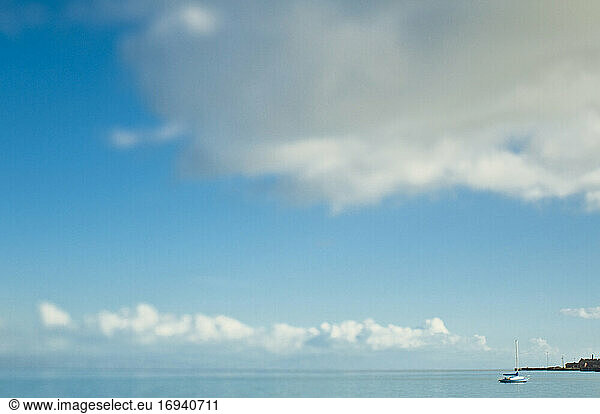 Clouds in sky over ocean with boat.