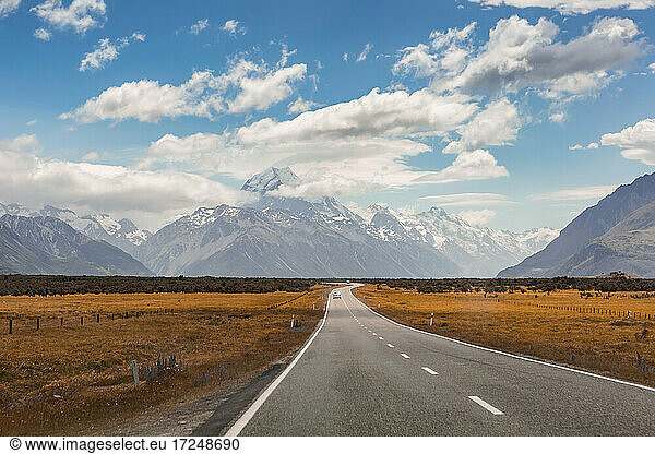 Clouds over asphalt highway stretching toward Southern Alps