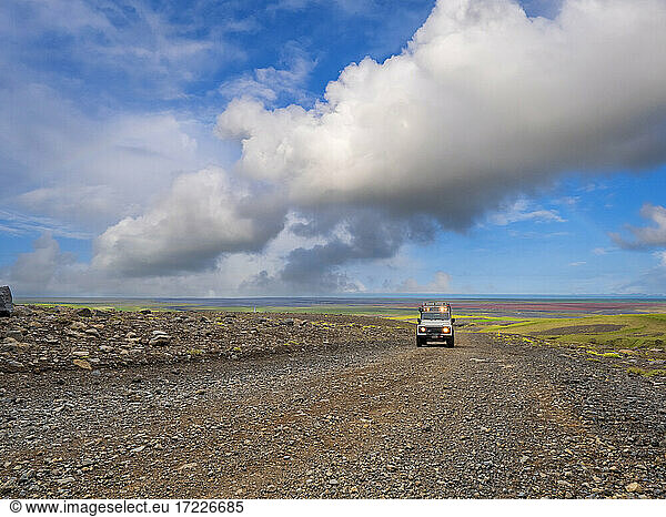 Clouds over off-road car driving along remote dirt road at Myrdalsjokull icecap