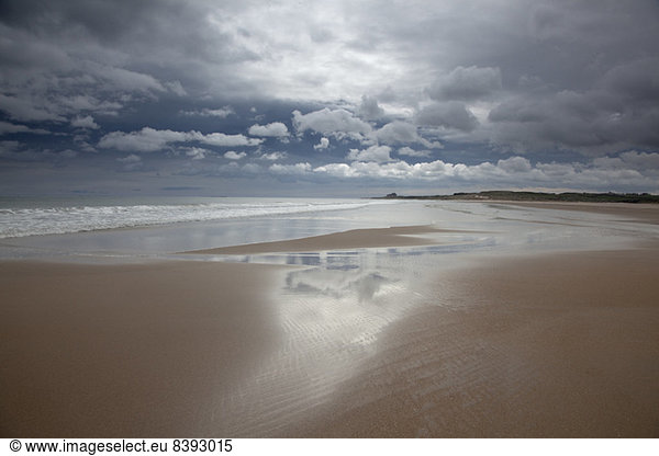 Clouds reflected in water on beach