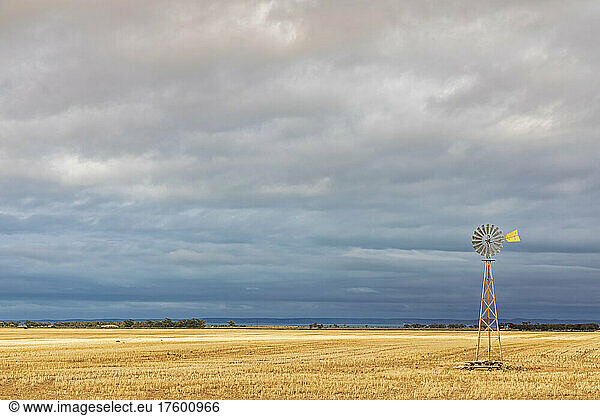 Cloudy sky over old windpump standing in field