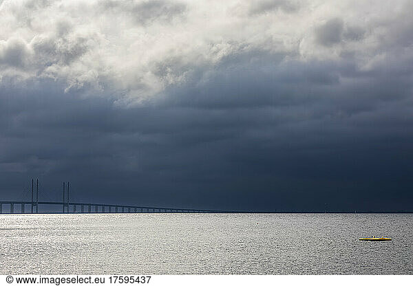 Cloudy sky over Sound strait with silhouette of Oresund Bridge in background