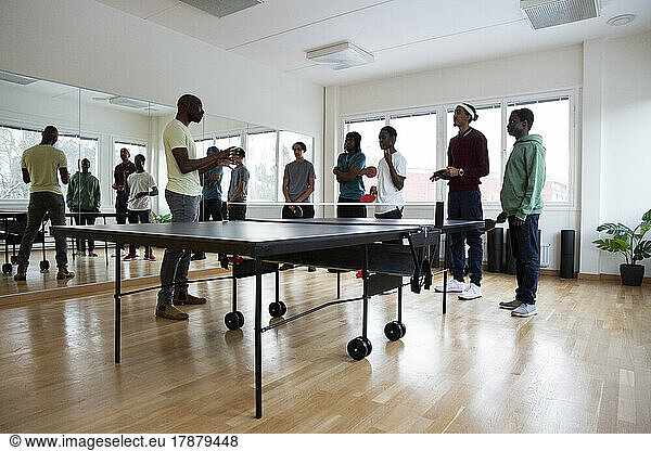 Coach giving table tennis instructions to students in games room