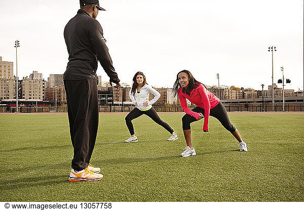 Coach training female athletes on playing field in city