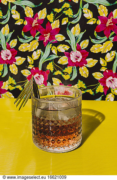Cocktail liquor kept on yellow table against flower background