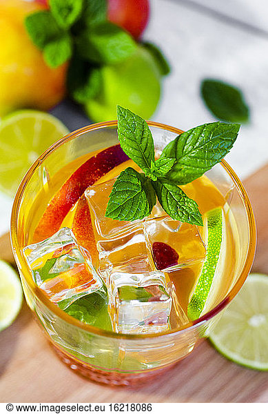 Cocktail with peach  mint and lime and ice cubes