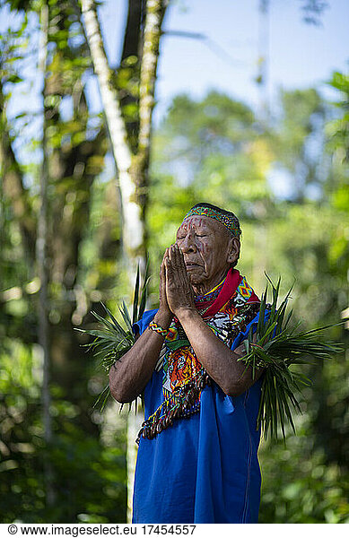 Cofan indigenous shaman praying with hands joined in Amazon rainforest