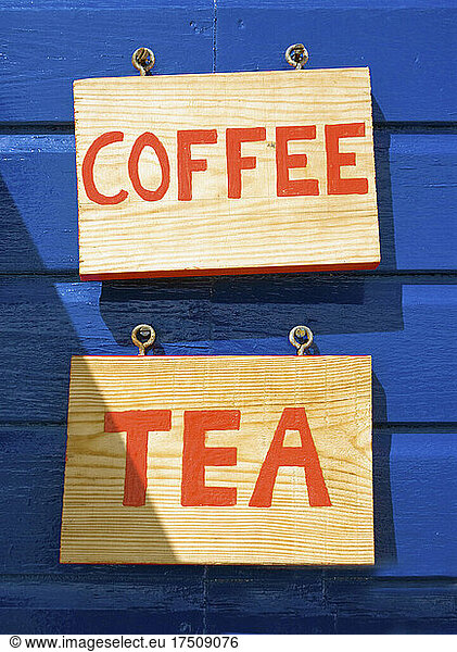 Coffee and tea signs on wooden wall or building exterior.