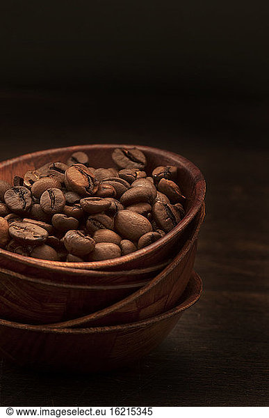 Coffee beans in stack bowls against black background  close up