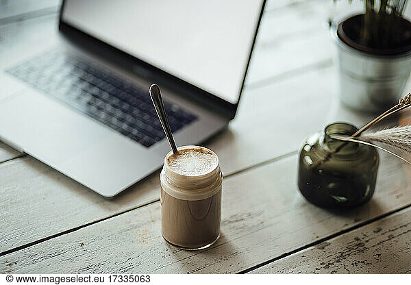 Coffee in jar by laptop on table at cafe