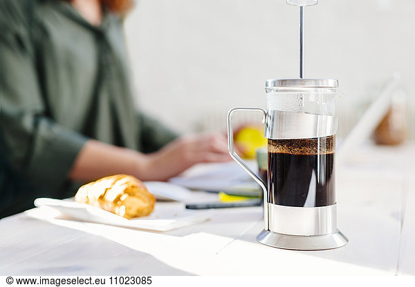 Coffee maker on table with businesswoman in background at office