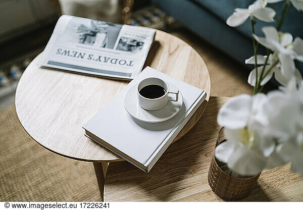 Coffee on book by newspaper on wooden table at home