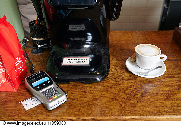 Coffee on counter in bakery  beside card payment machine