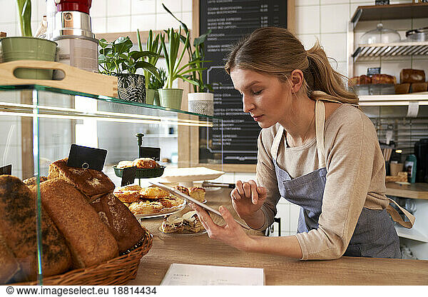 Coffee shop owner wearing apron using tablet PC