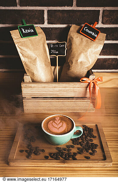 Coffee with latte art on wooden tray with coffee beans at cafe