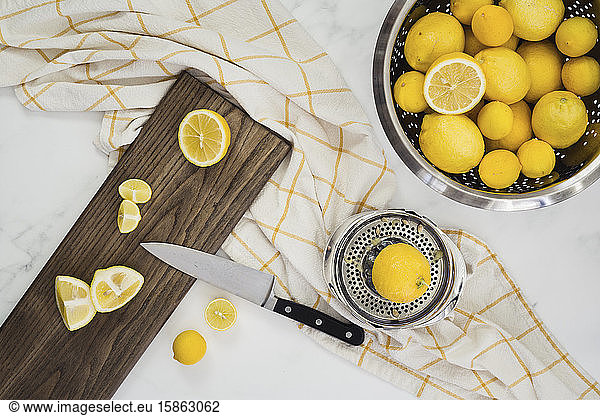 colander full of whole lemons with cut lemons on board with knife