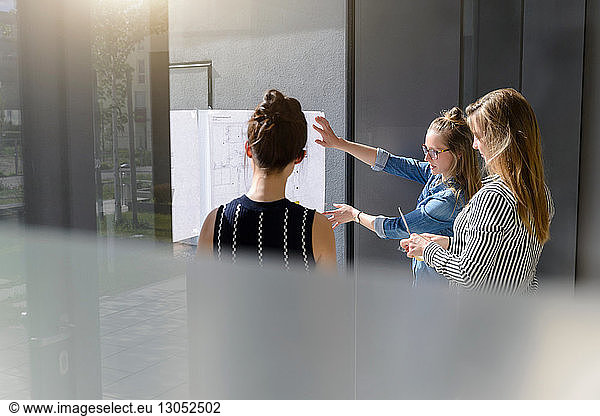 Colleagues discussing plans on glass wall