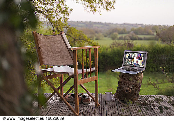 Colleagues video chatting on laptop screen on rural balcony