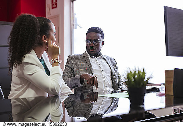 Colleagues working together at desk in office