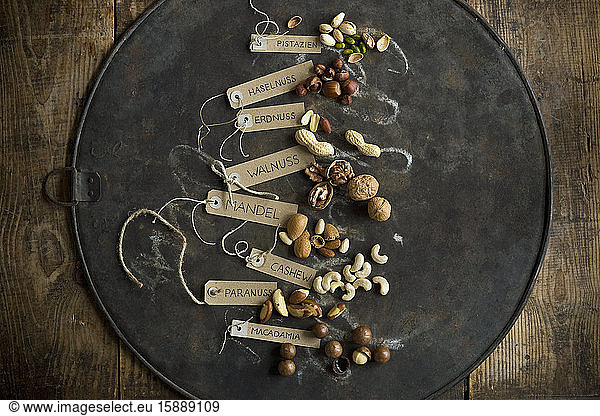 Collection of various nuts with name tags lying on rustic baking sheet