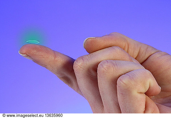 Color enhanced photograph of a contact lens on a fingertip.