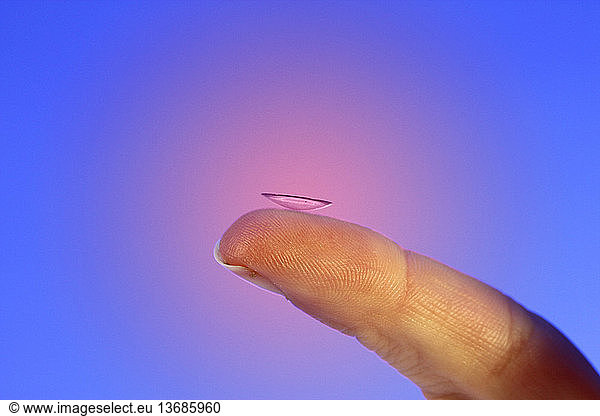 Color enhanced photograph of a contact lens on a fingertip.