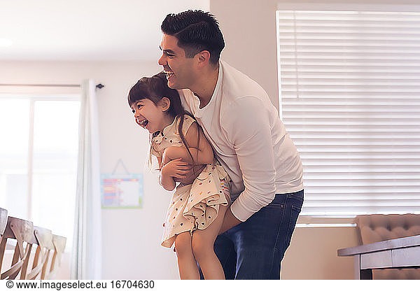 Color photo of dad holding daughter  both laughing.