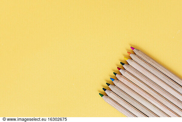 Colored pencils arranged on yellow background