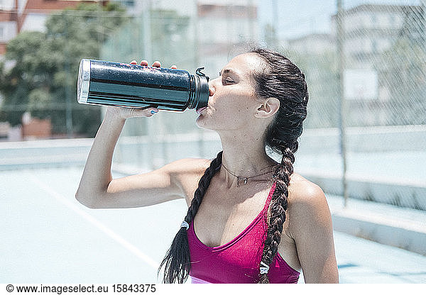 Colorful image of female athlete drinking water on court