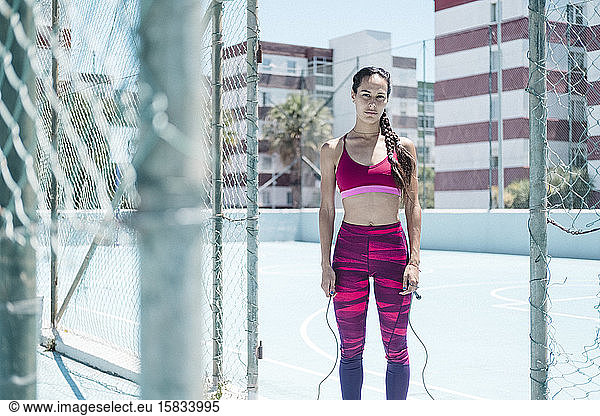 Colorful image of female athlete posing with jumping rope on court