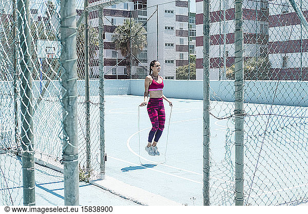Colorful image of female athlete skipping with jumping rope on court
