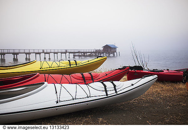 Colorful kayaks moored on shore in foggy weather